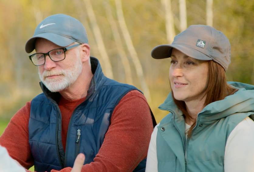 Two adults watching an adaptive biking activity