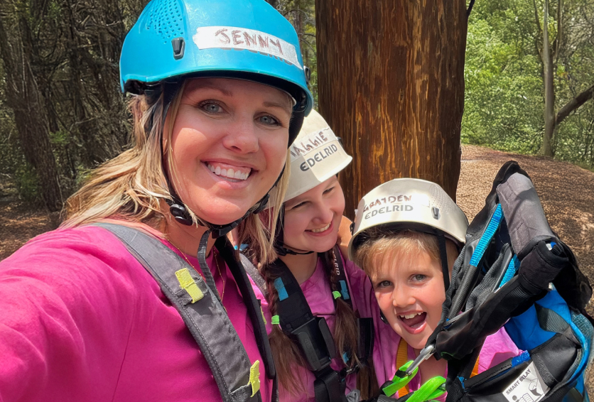 Family taking a selfie while wearing helmets at a ropes course